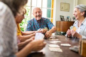 Senior friends playing cards, sitting at dining room and having good time