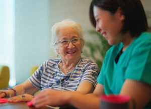 A senior woman is learning making origami as for physiotherapy activity.