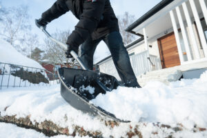 Man removing snow with a snow shovel in front of his house.