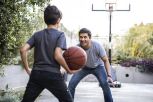 Hispanic father and son playing basketball in the backyard